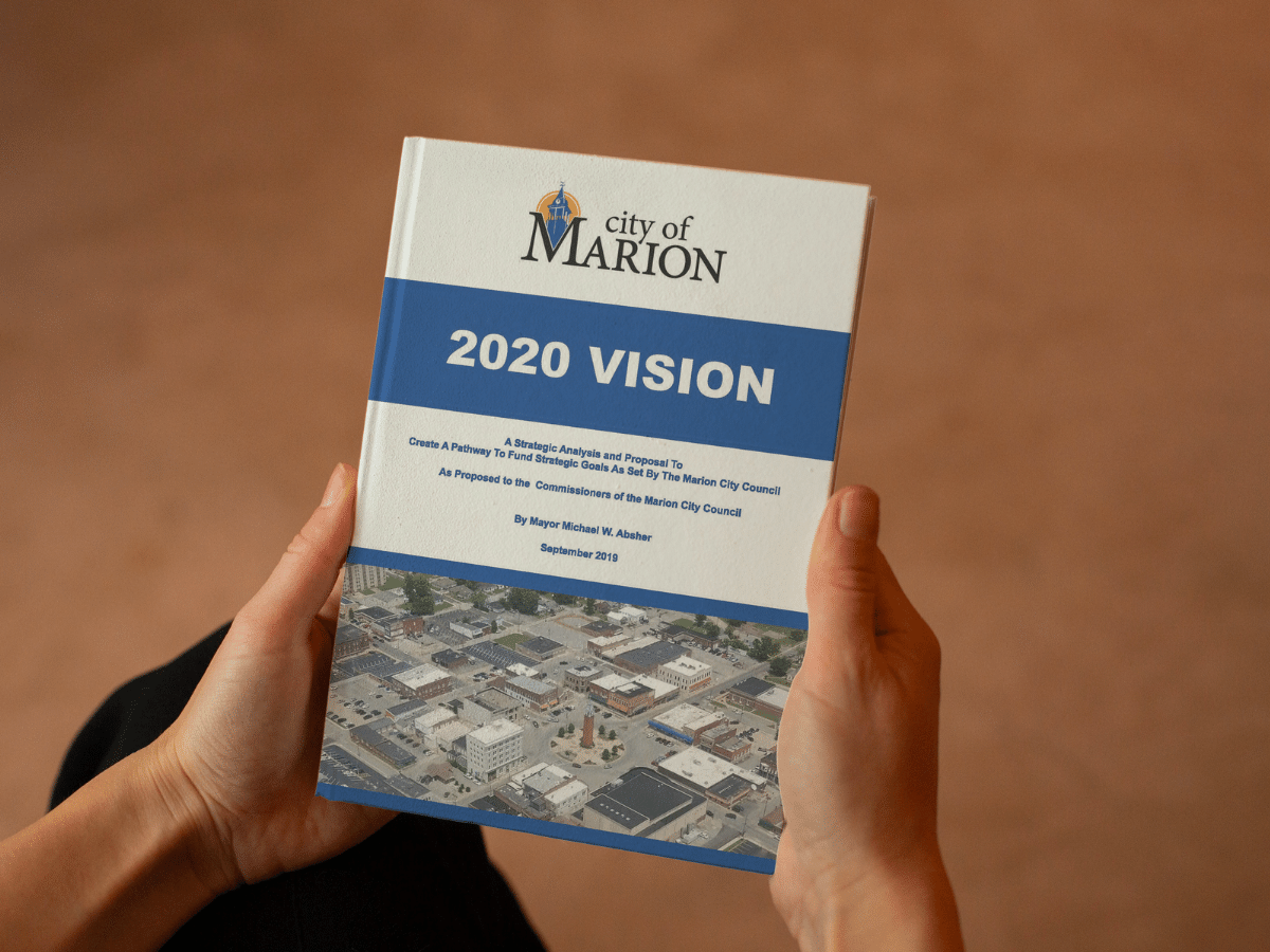 person holding book 2020 Vision City of Marion