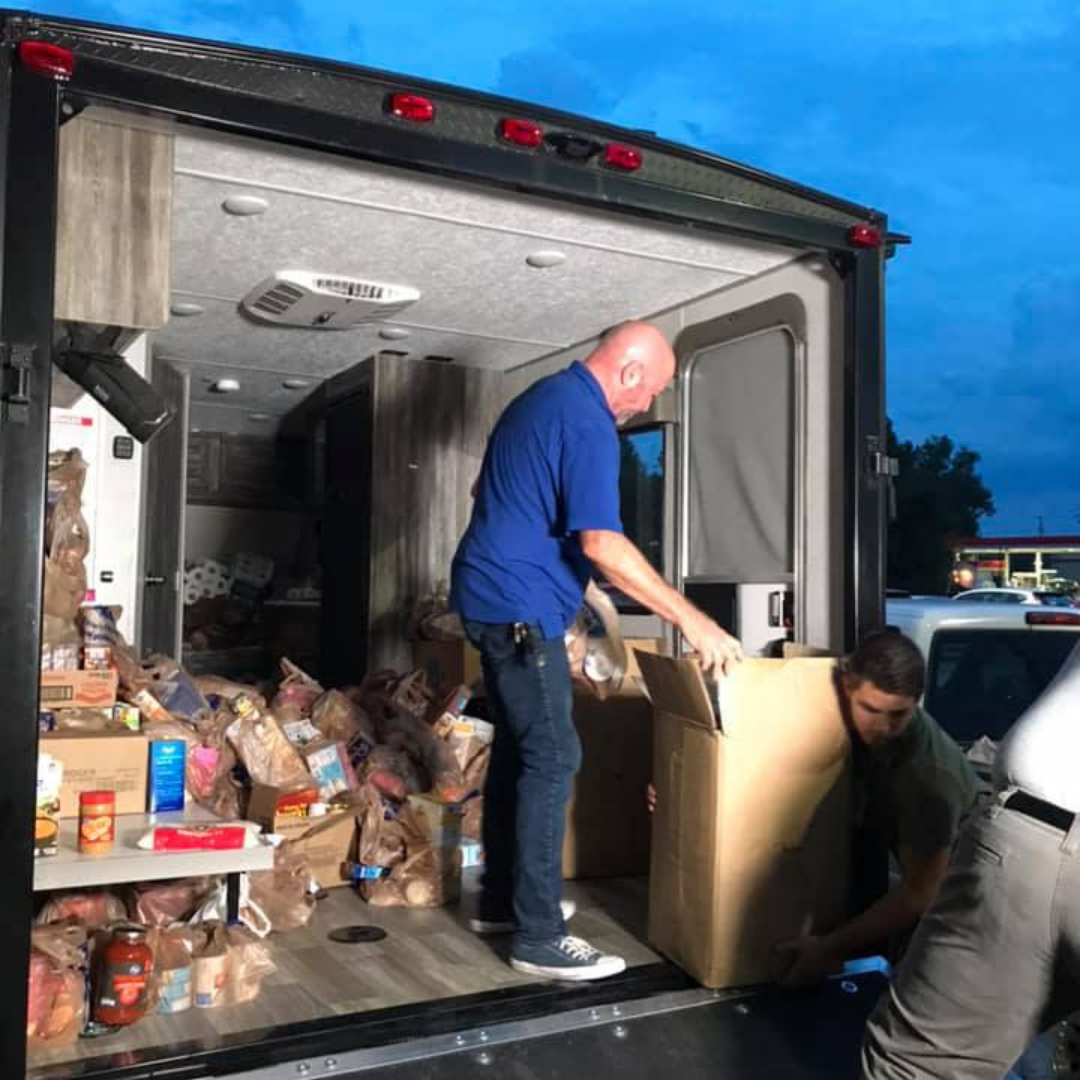 a volunteer unloads food donations out of the back of a box truck at the salvation army